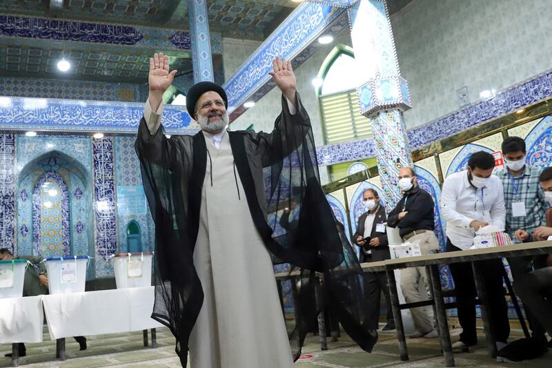 Mr Raisi gestures after he votes during presidential elections at a polling station in Tehran.