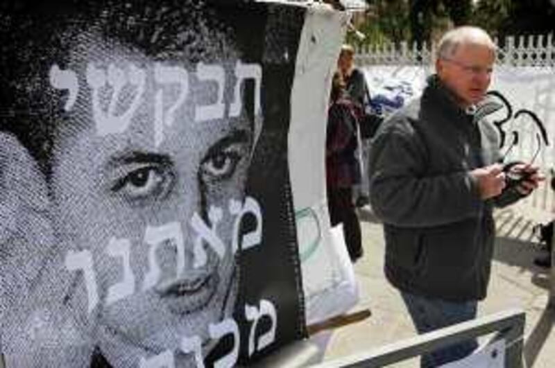 Noam the father of Israeli soldier Sgt. Gilad Schalit, who was captured by Hamas-allied militants in 2006, seen in the picture on left, stands next to a solidarity tent outside the Prime Ministers' residence in Jerusalem, Monday, March 9, 2009.  Schalit's parents have set up camp outside Prime Ehud Olmert's residence, vowing to stay there until the end of his term to try to pressure his government to bring their son home. Monday marked marked Gilad Schalit's 988th day in captivity. Hebrew writing on sign is a partial quote from an Israeli song. (AP Photo/Sebastian Scheiner) *** Local Caption ***  JRL103_MIDEAST_ISRAEL_PALESTINIANS.jpg