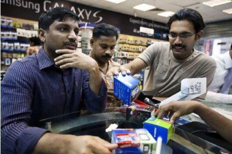 December 14, 2010 - Abu Dhabi, UAE - Men look at different mobile phone brands to decide what to buy at Golden Crown Mobiles on Defence Rd. in Abu Dhabi on Tuesday December 14, 2010. (Andrew Henderson/The National)