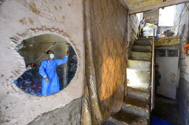 TOPSHOT - A worker disinfects a house in an impoverished neighbourhood in the central Iraqi holy city of Najaf on March 23, 2020 amid the COVID-19 coronavirus pandemic. / AFP / Haidar HAMDANI