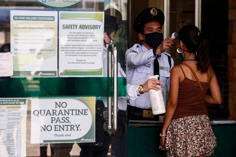 A security guard conducts a thermal check on a woman at a supermarket in Quezon City, Metro Manila, Philippines. EPA