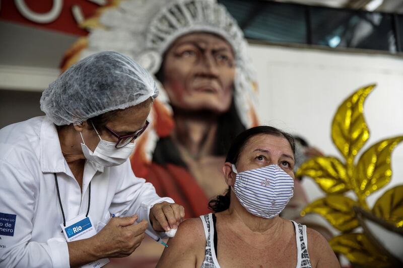 A woman receives a dose of CoronaVac vaccine against covid-19, developed by China's Sinovac Biotech,  at the street of Cacique de Ramos, where one of the most traditional carnival troupes resides in Rio de Janeiro, Brazil. EPA