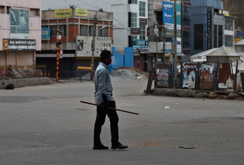 A plainclothes policeman holds a stick to prevent movement of people inside a containment zone during lockdown in Bengaluru, India. India's coronavirus tally is fourth in the world behind the US, Brazil and Russia. AP Photo