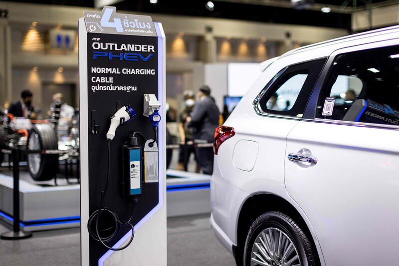 Charging components are displayed next to a Mitsubishi Outlander PHEV plug-in hybrid SUV car at the Thailand International Motor Expo 2021. AFP