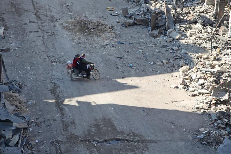 Syrian men ride a motorcycle through a damaged neighbourhood in Maaret Al-Numan city in Syria's northwestern Idlib province.  AFP