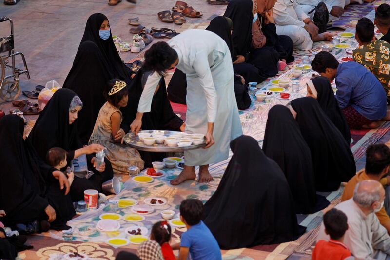 A young boy serves food to women attending a communal iftar on a street in the central Iraqi city of Najaf. Reuters