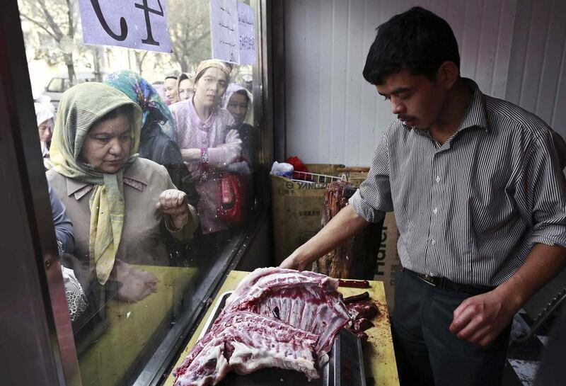 People wait to buy mutton at a butcher's shop in Xinjiang, China.