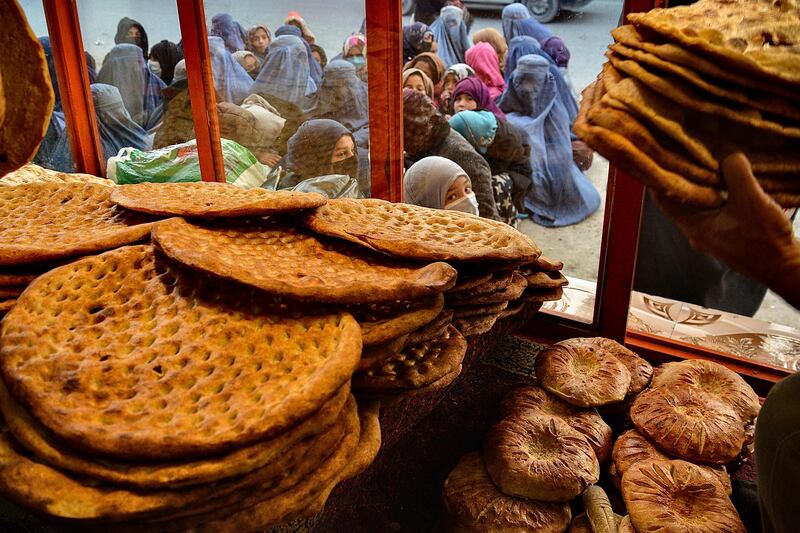 Afghan women and girls gather outside a Kabul bakery for food on February 19. AFP