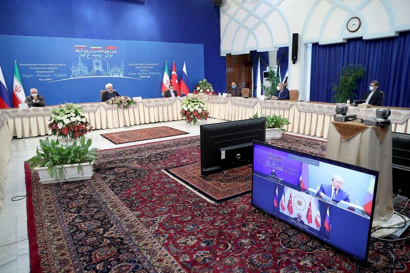 A handout picture provided by the Iranian presidency shows President Hassan Rouhani, accompanied by the Foreign Minister Mohmmad Javad Zarif, attending by video conference a trilateral meeting with the leaders of Turkey and Russia on the topic of Syria. AFP PHOTO