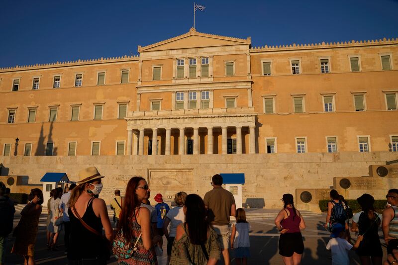 Tourists watch the changing of the Presidential guards ceremony outside the Greek parliament in central Athens.