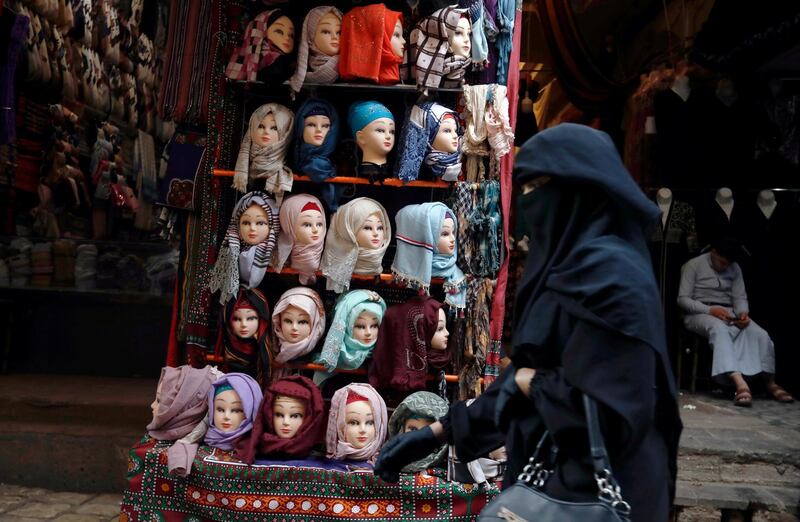 A woman passes mannequins in Muslim headscarves, at a market in Sanaa, Yemen. EPA