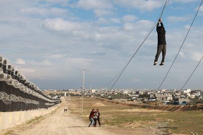Displaced Palestinian children play with a non-functioning electricity cable near the border fence between Gaza and Egypt. AFP