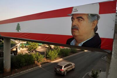 A car passes under a Lebanese flags with picture of slain Lebanese Prime Minister Rafik Hariri in Beirut, Lebanon, Tuesday, Aug. 18, 2020. A U.N.-backed tribunal on Tuesday convicted one member of the Hezbollah militant group and acquitted three others of involvement in the 2005 assassination of former Lebanese Prime Minister Rafik Hariri. (AP Photo/Bilal Hussein)