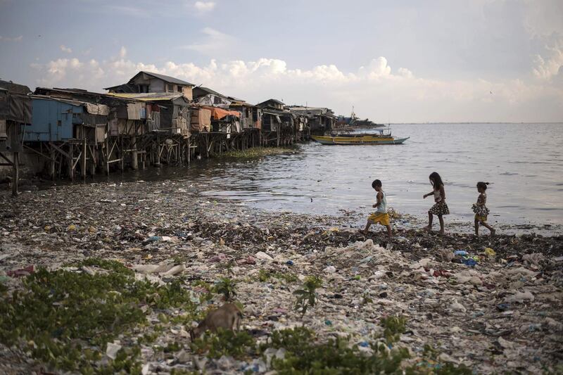 Children walking along a garbage-filled bay in Manila. Noel CELIS / AFP