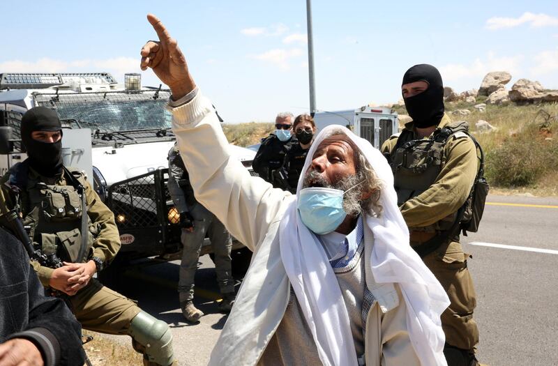 epa09124319 A Palestinian protester argues with Israeli security forces as he protests against Israeli settlement building activities on their land in the village of West Bank Yatta, near Hebron, 09 April 2021.  EPA/ABED AL HASHLAMOUN
