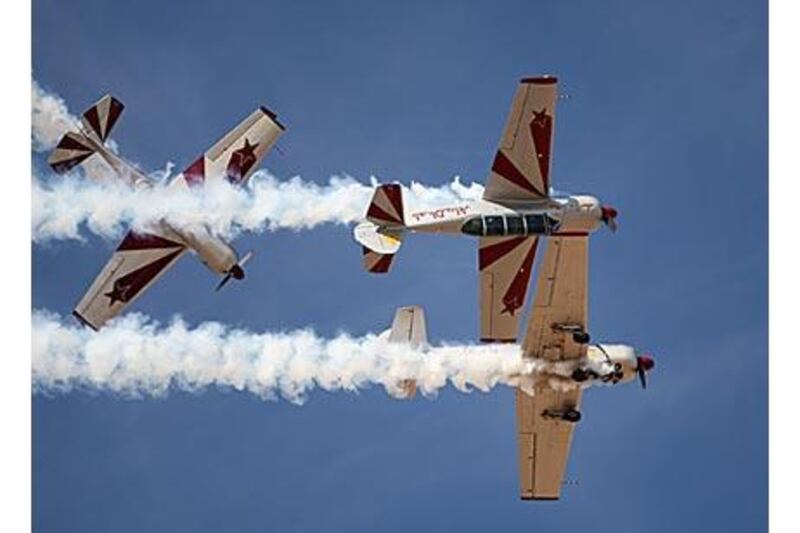 Two Yak 52s, right, from the flying team Yakitalia perform a manoeuvre called mirroring while a third loops around them at Al Ain Aerobatic Show last year.