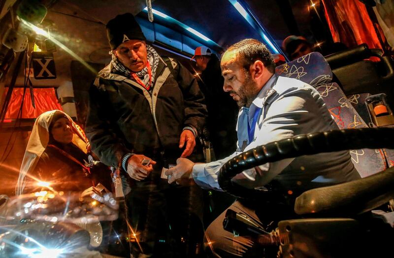 A Hamas police officer checks the travel documents of pilgrims to Mecca boarding a bus at the Rafah border crossing between the Gaza Strip and Egypt.    AFP