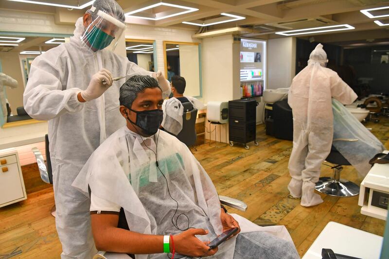 Staff at Shiva's Signature hair salon wearing Personal Protective Equipment (PPE) suits and face shields attend customers after personal grooming services were allowed to resume in Mumbai, India. AFP