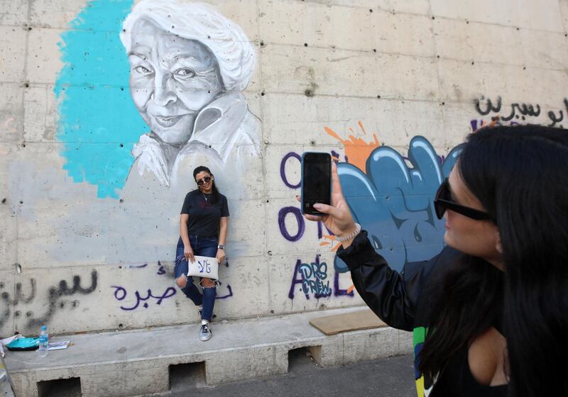 A Lebanese woman takes a photograph of her friend in front of the painting. AFP