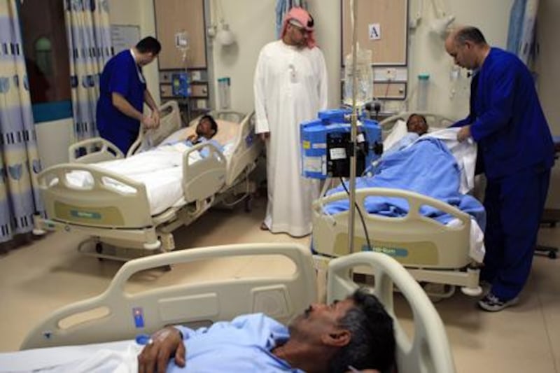 ABU DHABI - 27 MAR 2011- Salah al Din bin Ali (R) charge nurse treating food poisoned patients at Madinat Zayed Hospital, as Jasem Blush Mohammed al Mazroui (C) Patients affairs assistant looks on yesterday from Al jaber labour camp in Madinat Zayed in Western region of Abu Dhabi. Ravindranath K / The National