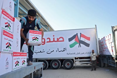 A Palestinian labourer empties boxes of aid from an Egyptian aid truck at the Rafah border crossing, which connects the Gaza Strip to Egypt, on May 23, 2021.  / AFP / SAID KHATIB
