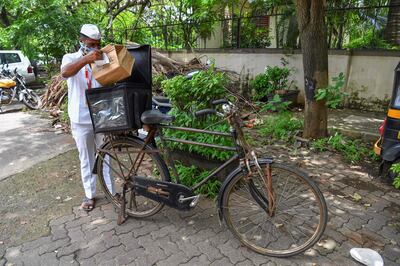 One of Mumbai's tiffin delivery men or "Dabbawallas", Pandurang Jadhav, prepares to deliver an order after collecting it from a restaurant in Mumbai. After the pandemic shut offices and put Mumbai's renowned lunchbox deliverymen out of work, the 130-year-old tiffin delivery network tied up with a restaurant chain, on June 22, 2021, in Mumbai, India. AFP