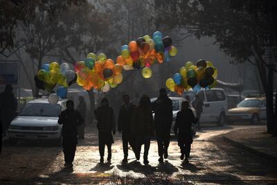Afghan balloon vendors walks past the Ministry of Public Works a day after a deadly militant attack in Kabul on December 25, 2018. An hours-long gun and suicide attack on a Kabul government compound killed at least 43 people, the health ministry said December 25, making it one of the deadliest assaults on the Afghan capital this year.
 / AFP / WAKIL KOHSAR
