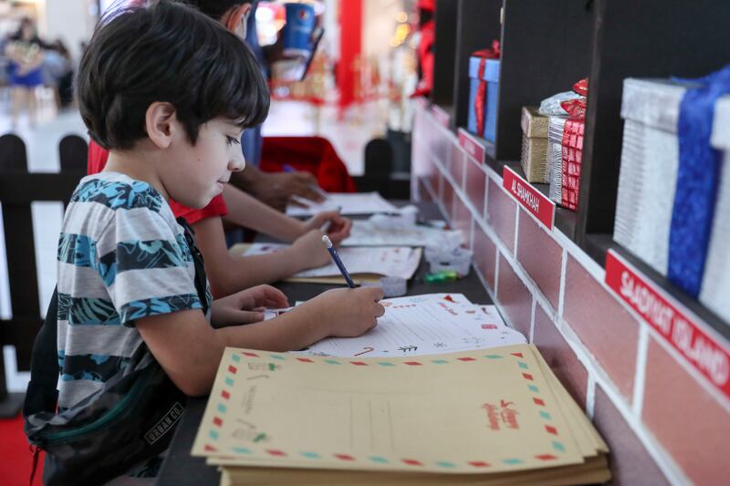 A young boy writes Santa a letter at The Galleria Mall Al Maryah Island. Khushnum Bhandari / The National