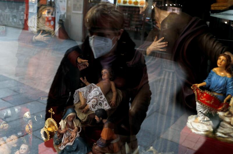 A woman wearing a face mask looks at religious figurines in a shop window, amid the coronavirus disease outbreak in Madrid, Spain. Reuters