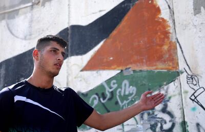 Palestinian student at Al-Quds University Moayad Afaneh, 22, gestures during an interview with AFP by the wall separating East Jerusalem from the Palestinian village of Abu Dis, in the occupied West Bank village, on September 23, 2020. Two decades on from the Second Intifada, Palestinians who have grown up in the shadow of the uprising find themselves surrounded by barriers with little hope for the future. / AFP / Emmanuel DUNAND
