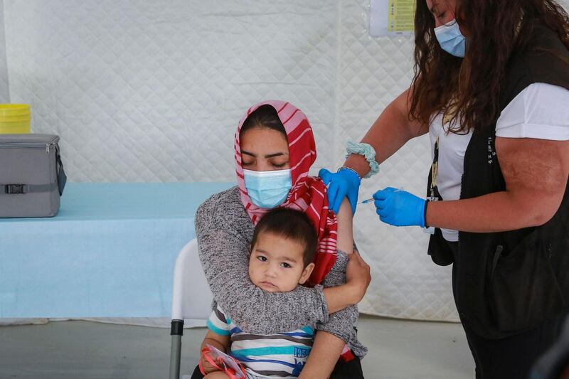 A woman holding her child receives a vaccine in the Mavrovouni refugee camp on the Greek island of Lesbos. AFP