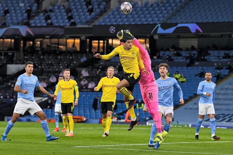 Manchester City's Brazilian goalkeeper Ederson (3R) punches the ball away from the head of Dortmund's German midfielder Mahmoud Dahoud during the UEFA Champions League first leg quarter-final football match between Manchester City and Borussia Dortmund at the Etihad Stadium in Manchester, north west England, on April 6, 2021. (Photo by Paul ELLIS / AFP)