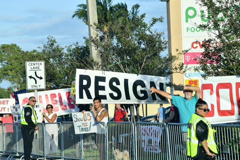 Protestors hold signs and banners against Donald Trump after his arrival in West Palm Beach, Florida on April 18, 2019. AFP