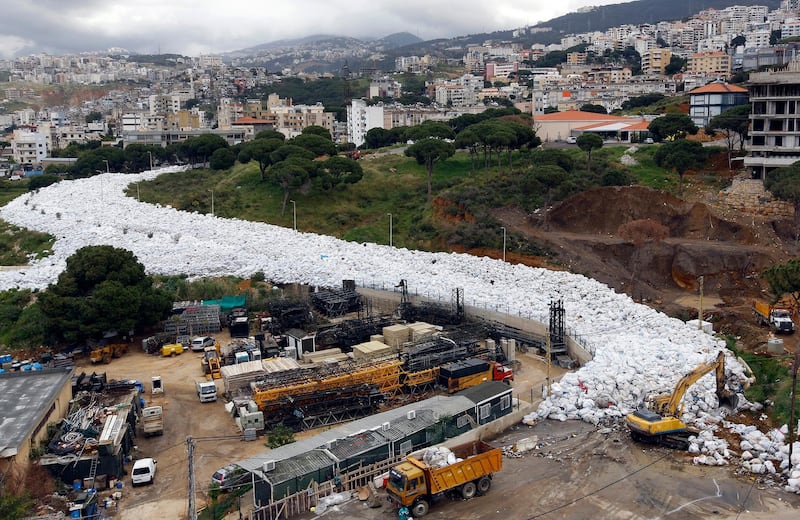 Trucks are seen next to piles of garbage in Jdeideh, a Beirut suburb, ahead of moving it to the country's largest landfill of Naameh, just south of the Lebanese capital, on March 20, 2016. - Trucks began moving stacked rubbish outside the Lebanese capital under a plan adopted by the Lebanese government to put an end to the waste crisis that has been going on for eight months, according to an AFP photographer. Lebanon said on March 12 it would temporarily reopen a landfill to ease the crisis as thousands of people demonstrated in Beirut against the waste pile-up. Rubbish has piled up on beaches, in mountain forests and river beds across Lebanon since the closure in July of the country's largest landfill at Naameh. (Photo by ANWAR AMRO / AFP)