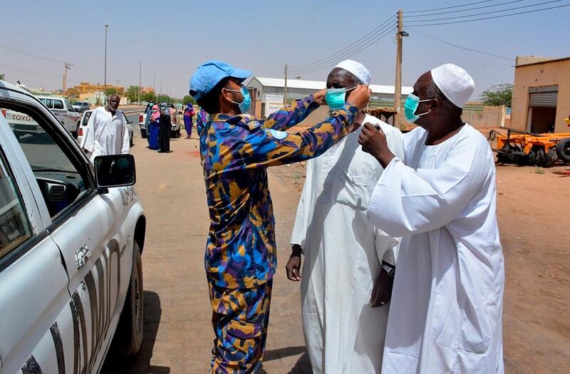 In this June 8, 2020 photo released by the United Nations African Union Mission in Darfur (UNAMID), Bangladeshi peacekeepers provide masks and hand sanitizers to local population in the streets of El Fasher, town in North Darfur as part of their awareness campaign on COVID-19, in Sudan. In the sprawling refugee camps of Sudan's Darfur, officials say people are falling sick and dying at astonishing rates. Humanitarian workers and medical personnel believe the coronavirus is spreading unchecked and untracked through Sudanâ€™s most marginalized territory. (UNAMID via AP)