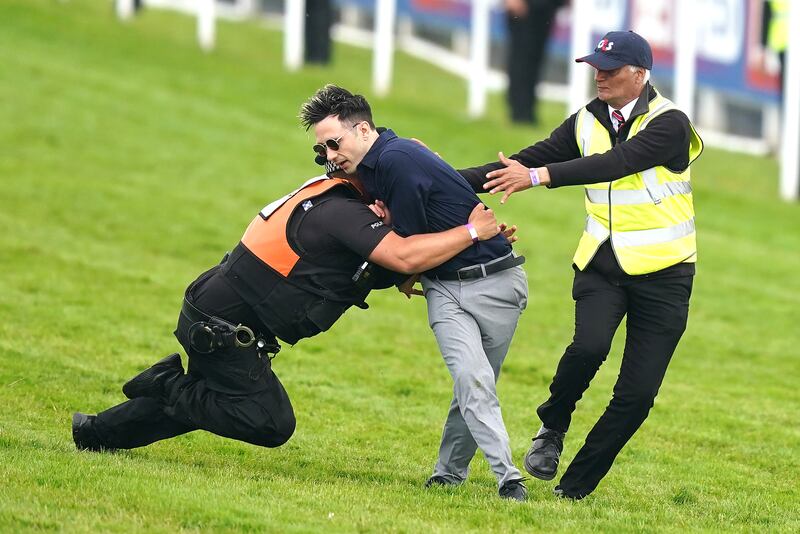 A protester is tackled by police and stewards after storming the racecourse shortly before the start of the Epsom Derby. PA