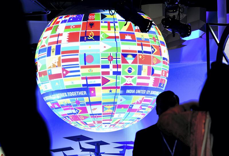 Visitors walk past a sphere featuring flags of countries of the world displayed at the pavillion of India on November 8, 2017 during the COP23 United Nations Climate Change Conference in Bonn, Germany. / AFP PHOTO / PATRIK STOLLARZ