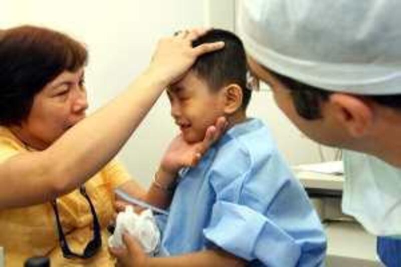 DUBAI . 8th July. 2009. BOY WHO CAN'T CRY. Seven-year-old James Lumasag supported by his mother Merlyn is examined by Dr.Andrea Sciscio, Consultant Ophthalmic Surgeon, before his operation at Moorfields Eye Hospital in Dubai yesterday(weds). Stephen Lock  /  The National . *** Local Caption ***  SL-eye-001.jpg