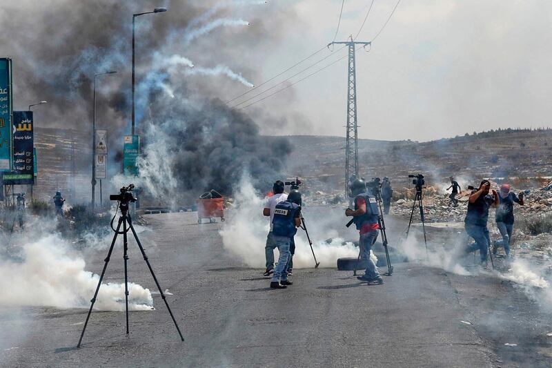 Journalists run for cover from tear gas canisters fired by Israeli forces during a demonstration near the Jewish settlement of Beit El in the occupied West Bank.  AFP