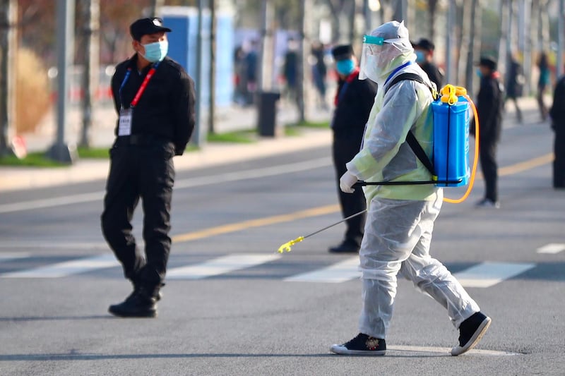 A worker in a protective suit sprays disinfectant on the street during the 2020 Shanghai marathon. AFP