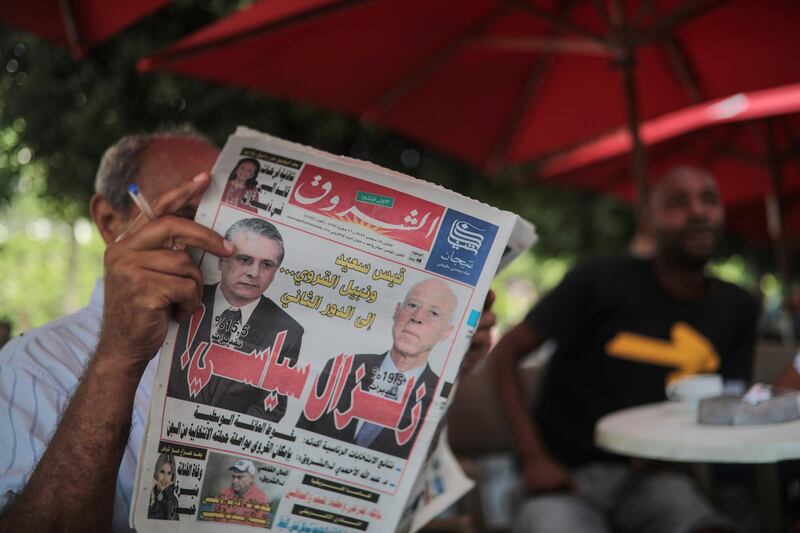 A man reads Al-Shorouk daily newspaper showing candidates Kais Saied, right, ) and Nabil Karoui on its front-page, a day after the first round of presidential elections, in a coffee shop in Tunis, Tunisia, Monday, Sept. 16, 2019. A polling firm projected Sunday that an independent outsider candidate and a jailed media magnate will head to Tunisia's presidential runoff, after a roller coaster, 26-candidate election. Headline in Arabic reads "Political earthquake". (AP Photo/Mosa'ab Elshamy)