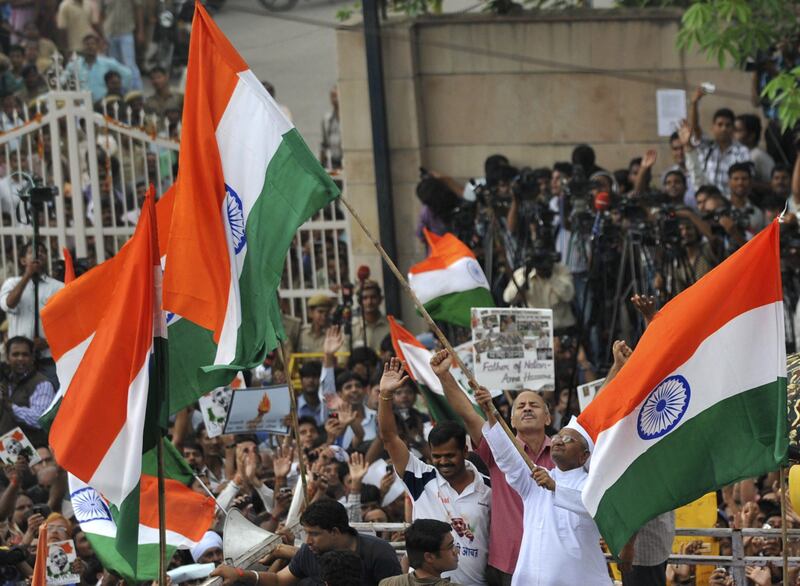 Indian social activist Anna Hazare (C) waves the Indian national flag as he stands on the back of a vehicle outside Tihar Jail in New Delhi on August 19, 2011.  Indian activist Anna Hazare has left jail to start a two-week public fast likely to fuel an eruption of angry protests over corruption that has left the government stumbling for a response. Thousands of frenzied, flag-waving supporters cheered the diminutive 74-year-old as he walked from the gates of Delhi's Tihar jail -- his de-facto campaign headquarters since he was taken into police custody three days ago. AFP PHOTO/Sajjad HUSSAIN
 *** Local Caption ***  637831-01-08.jpg