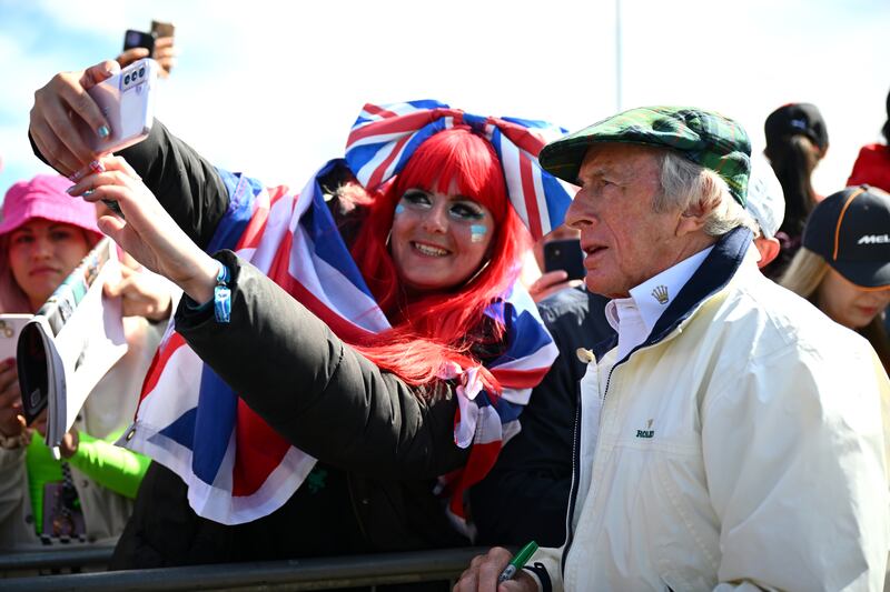 Sir Jackie Stewart signs autographs before entering the paddock. Getty