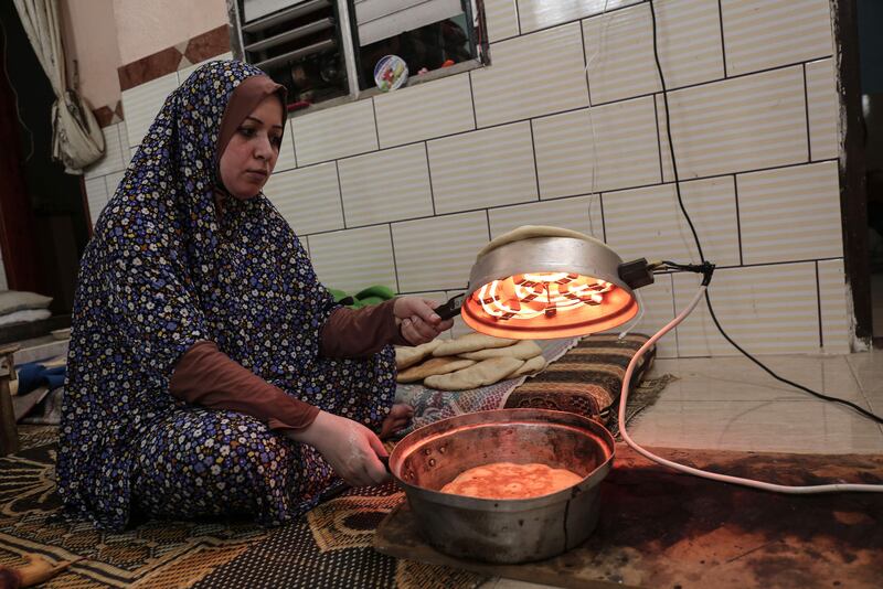 (FILES) This file photo taken on August 3, 2017 shows a Palestinian woman preparing bread during the few hours of mains electricity supply they receive every day, at Rafah refugee camp in the southern Gaza Strip.  / AFP PHOTO / SAID KHATIB