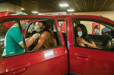 A health worker inoculates a man with a dose of the Covaxin vaccine against the Covid-19 coronavirus during  a drive-in vaccination center at Select city mall in New Delhi on May 28, 2021. / AFP / Prakash SINGH
