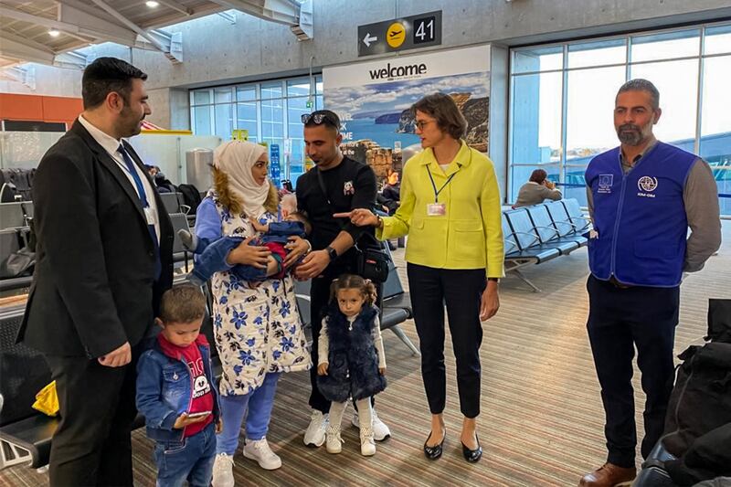 German ambassador to Cyprus Anke Schlimm with a family of asylum seekers, who are among 48 migrants being transferred to Germany, at the island's Larnaca International Airport. German Foreign Ministry / AFP