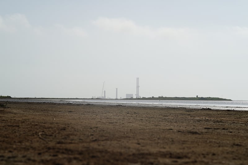 A SpaceX rocket rises in the distance.