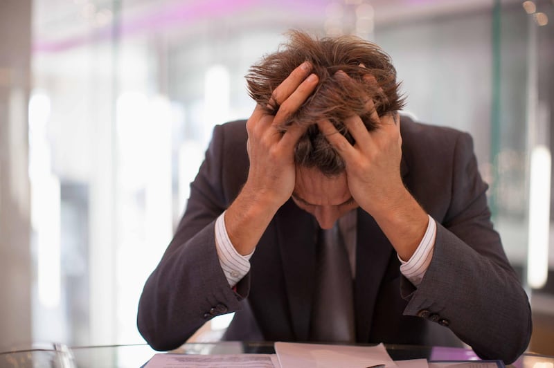 Frustrated businessman sitting at desk with head in hands. Getty Images
