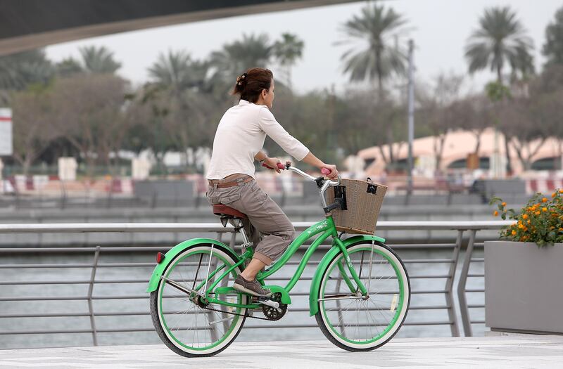DUBAI , UNITED ARAB EMIRATES – Feb 15 , 2017 : One of the woman enjoying her cycle ride during the cloudy weather at Dubai Water Canal in Dubai. ( Pawan Singh / The National ) For News / Online / Standalone. *** Local Caption ***  PS1502- WEATHER06.jpg