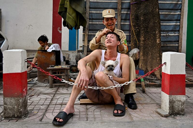 A man removes stray white hairs for his friend on a street in Hanoi, Vietnam. AFP